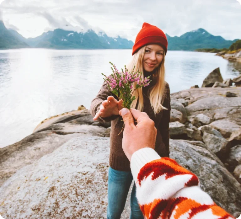 Foto von einer Frau, der an einem See ein Blumenstrauß gereicht wird